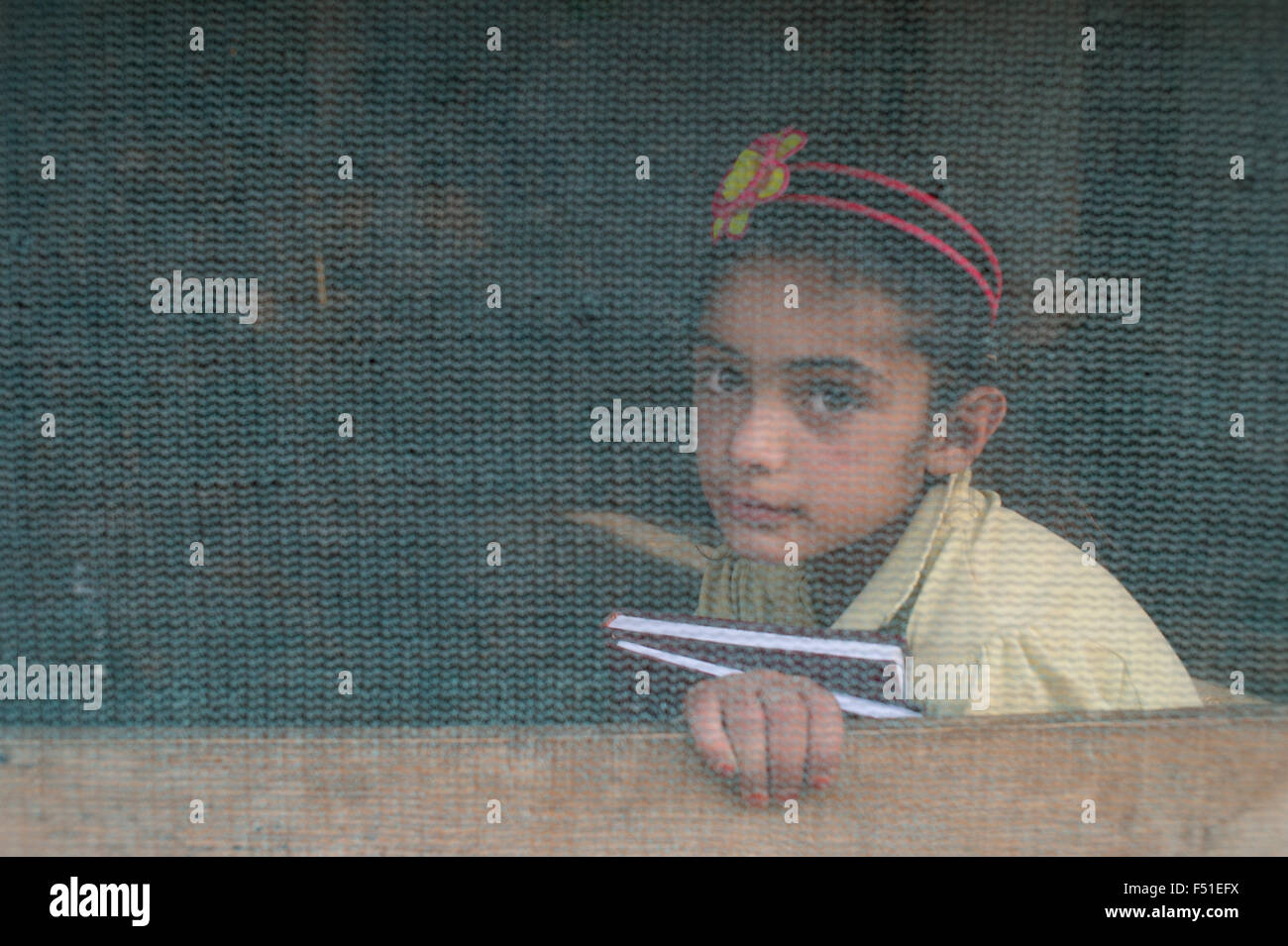 Syrian girl refugee holding her school books inside her tents provided by the UN. Zahle, Lebanon 2015 Stock Photo