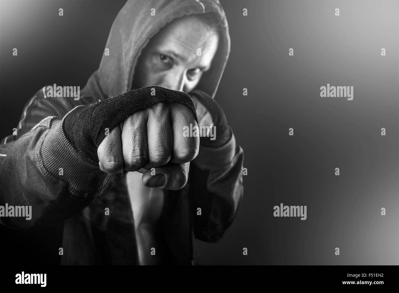Black and white fist of young dangerous man closeup. strong serious  athletic man wearing hoodie shirts standing in boxing pose Stock Photo