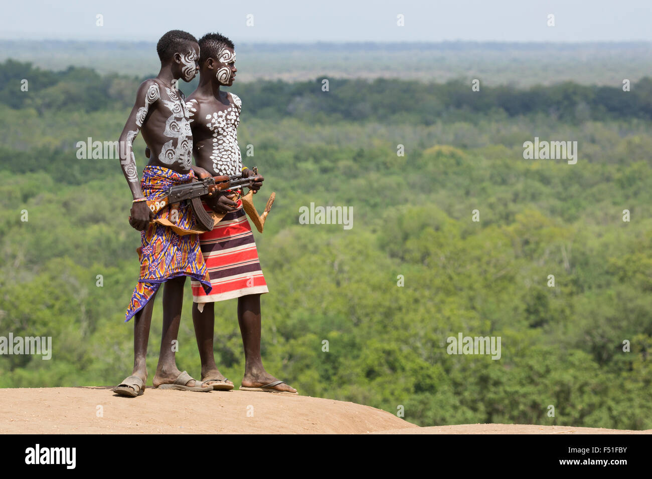 Young male Karo tribe boys with AK-47 rifle . Omo Valley, Ethiopia Stock Photo