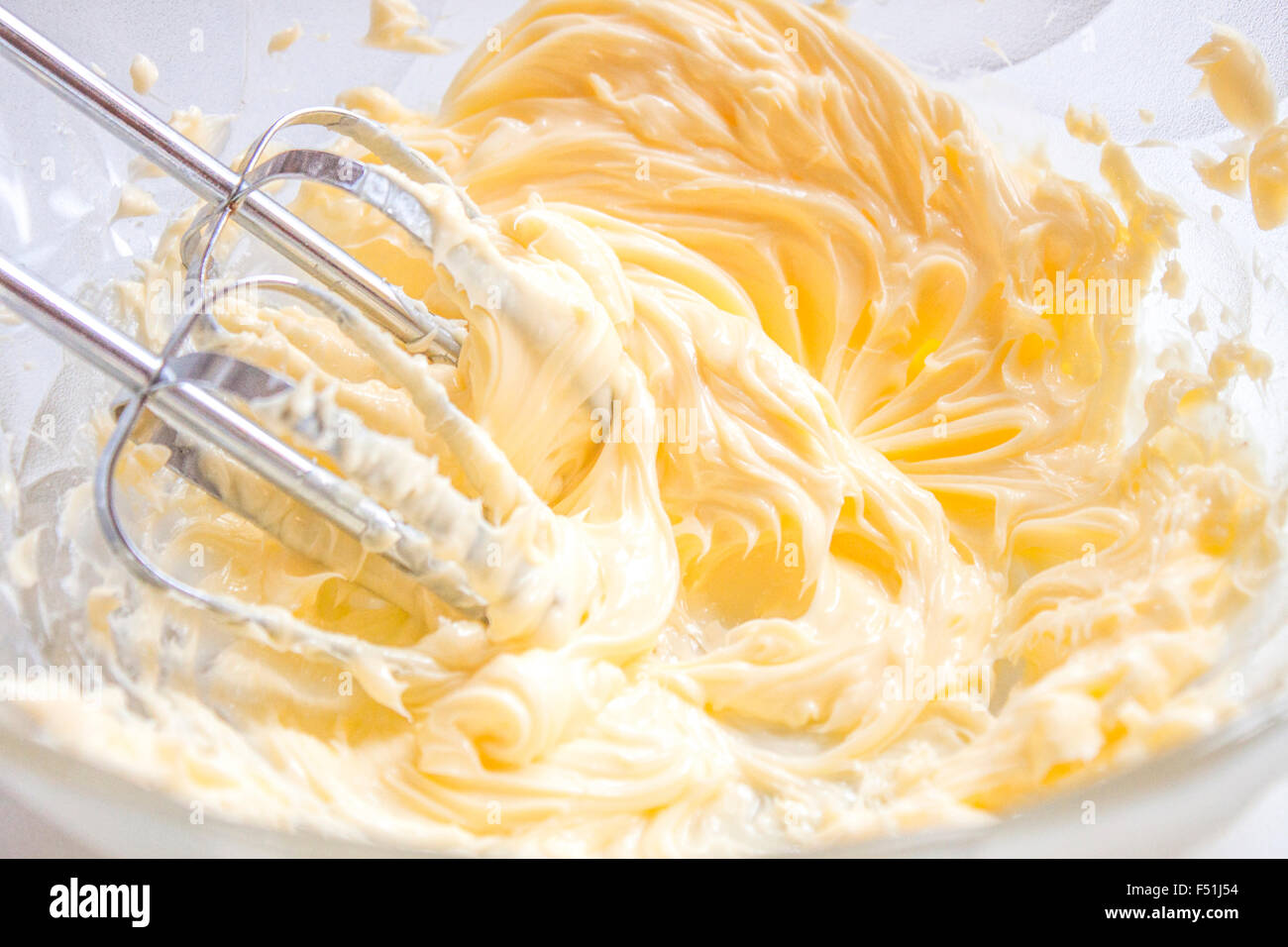 Whisking butter, in a bowl full of butter and egg yolks Stock Photo