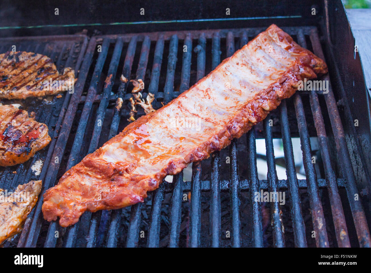 Pork loin ribs, near grilled pork loin, on a gas barbeque Stock Photo