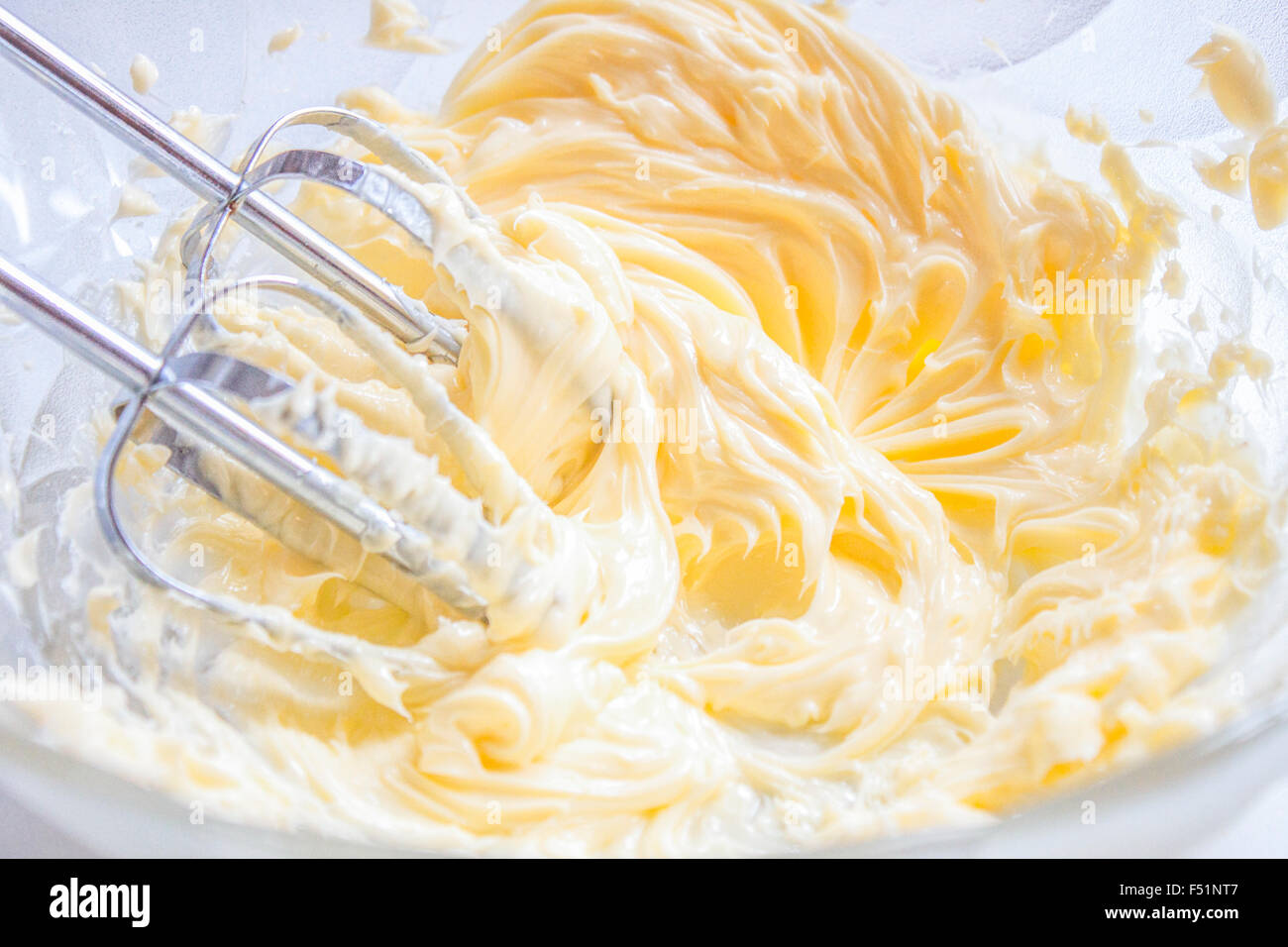 Whisking butter, in a bowl full of butter and egg yolks Stock Photo