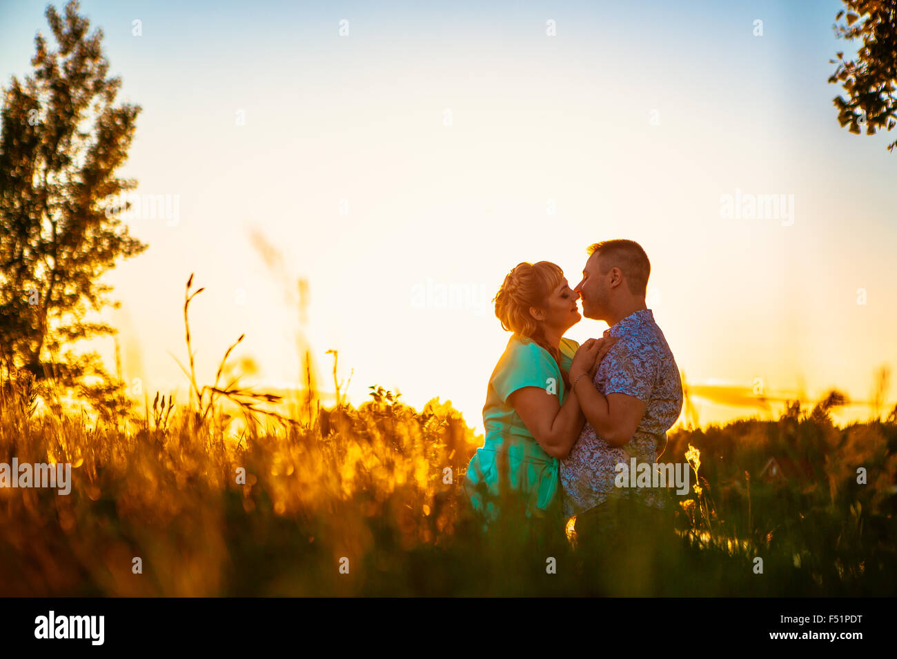 Romantic couple standing and kissing on background summer meadow sunset ...