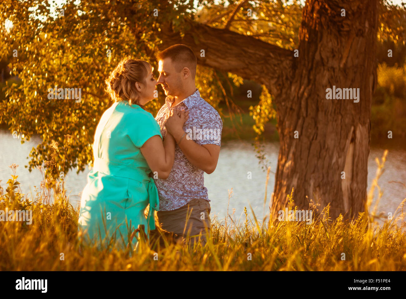 Romantic couple standing and kissing on background summer lake sunset ...