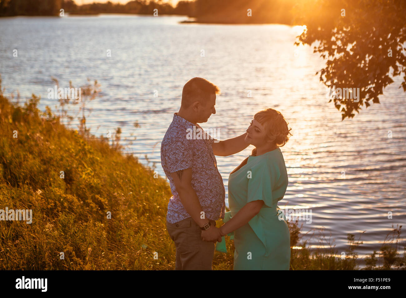 Romantic couple standing and kissing on background summer lake sunset ...