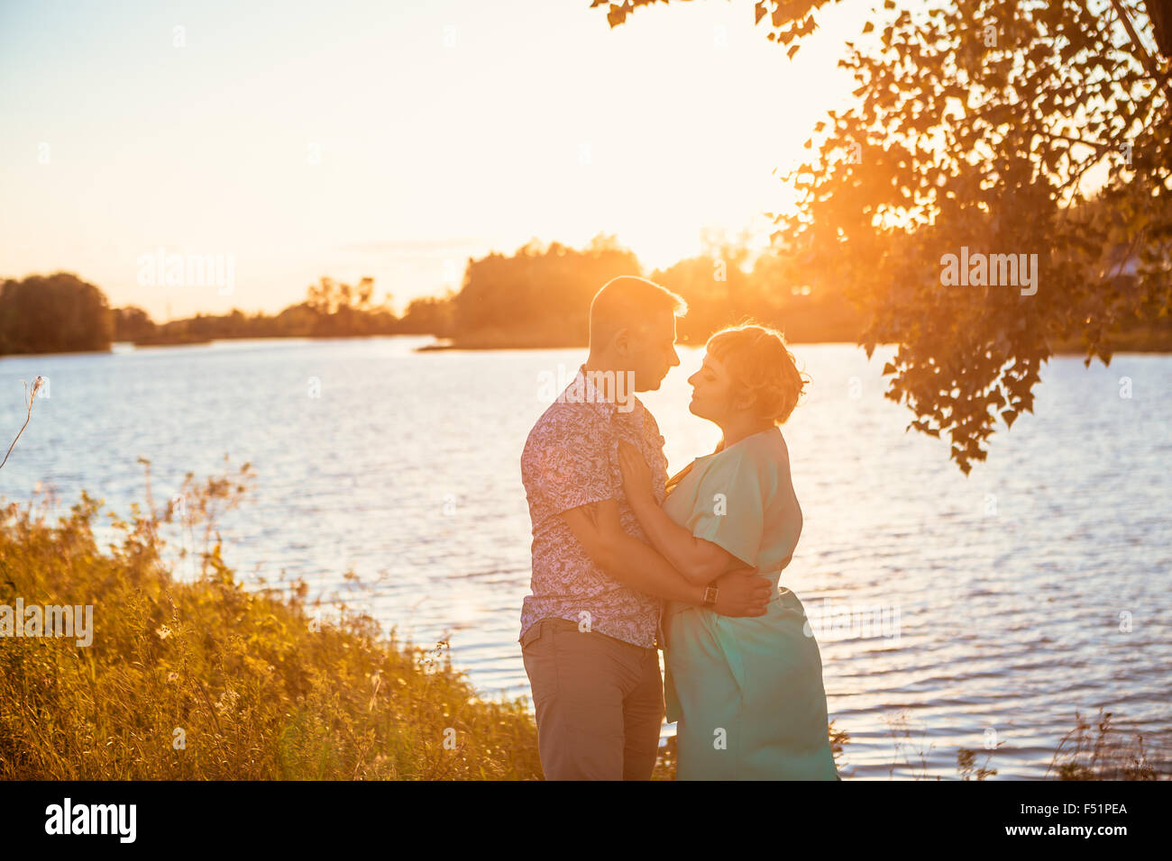 Romantic couple standing and kissing on background summer lake sunset ...