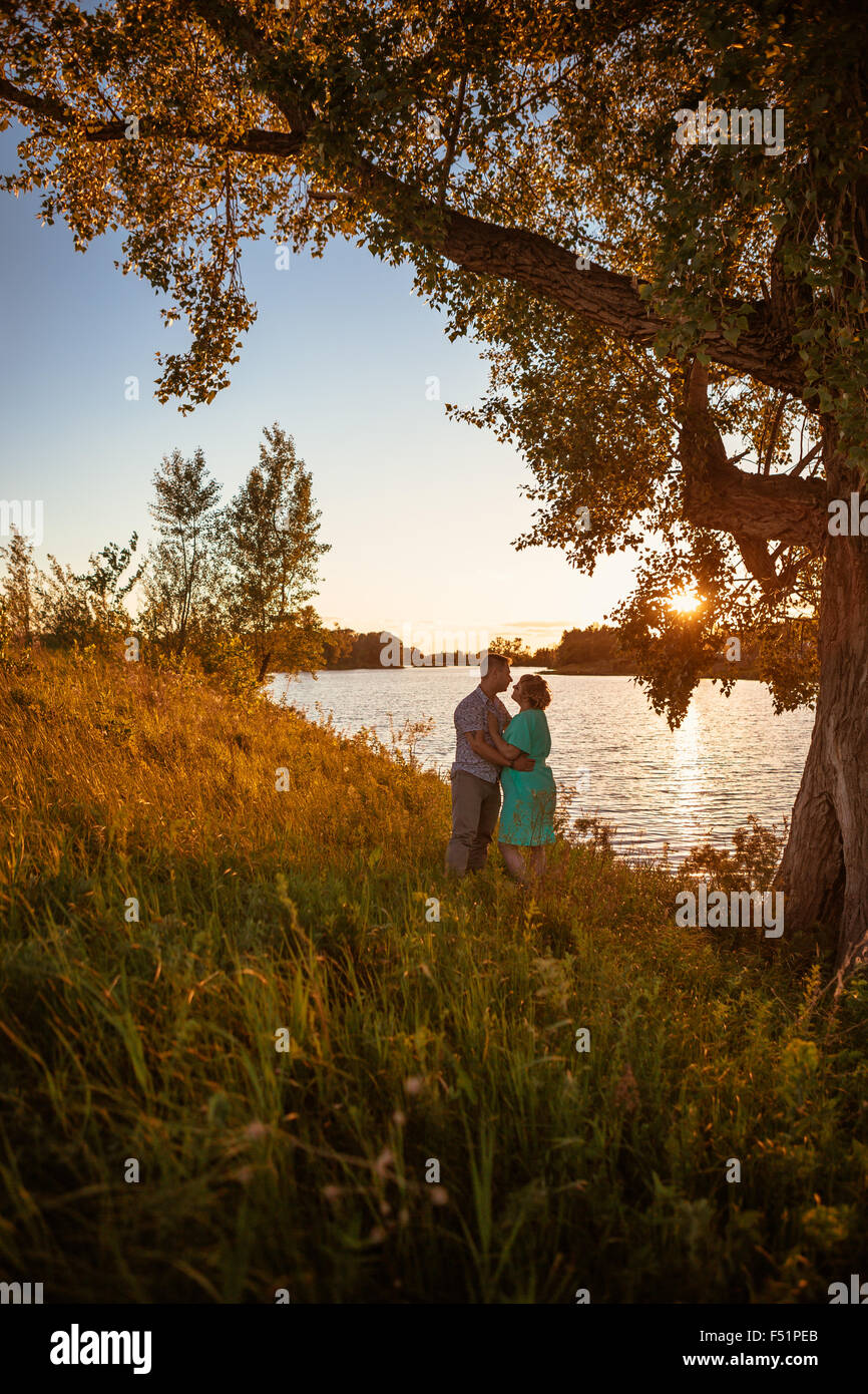 Romantic couple standing and kissing on background summer lake sunset ...