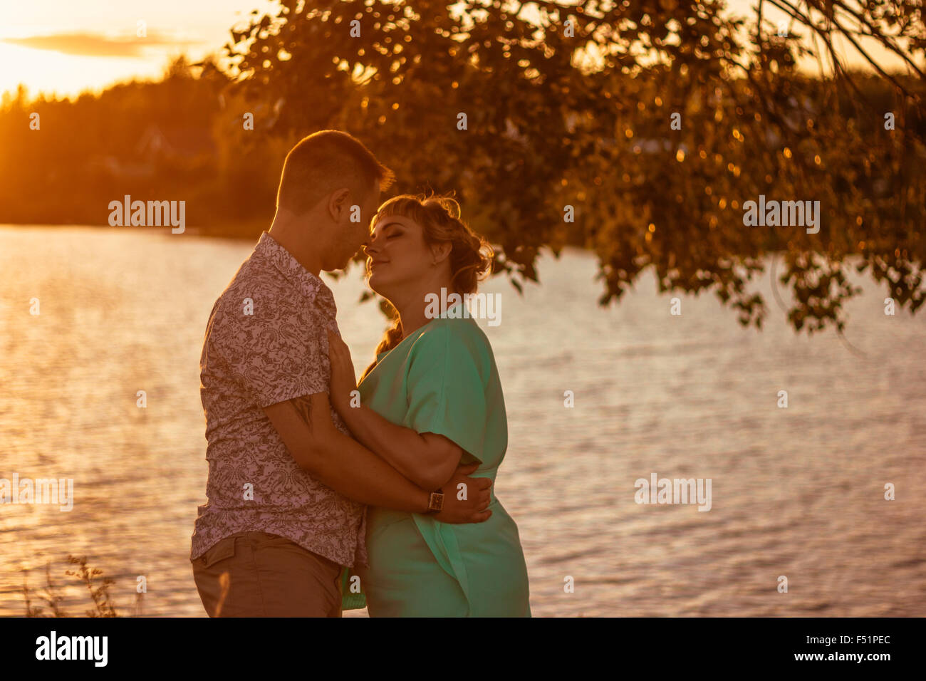 Romantic couple standing and kissing on background summer lake sunset ...
