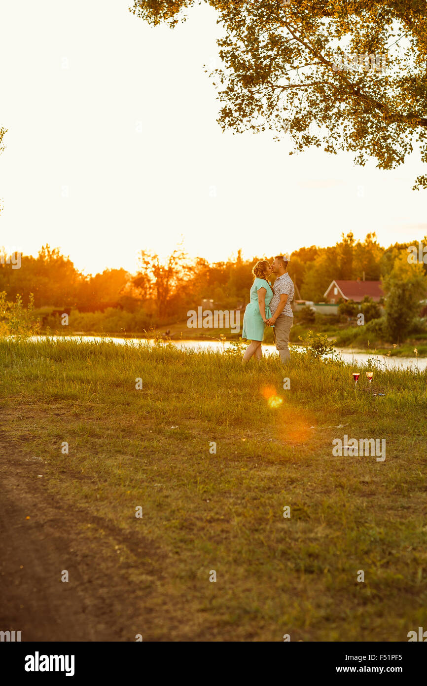 Romantic couple standing and kissing on background summer meadow sunset ...