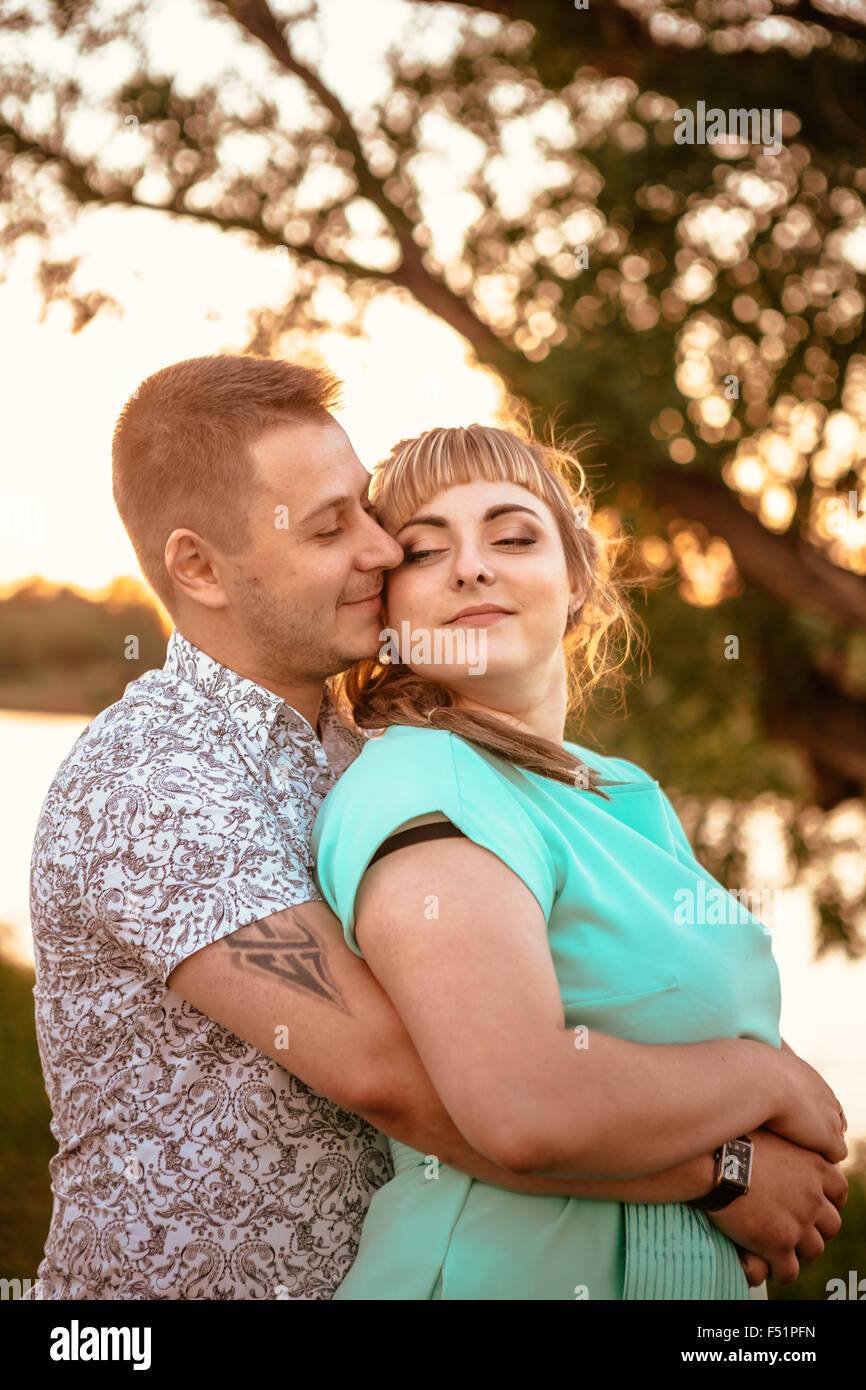 Romantic couple standing and kissing on background summer meadow sunset ...