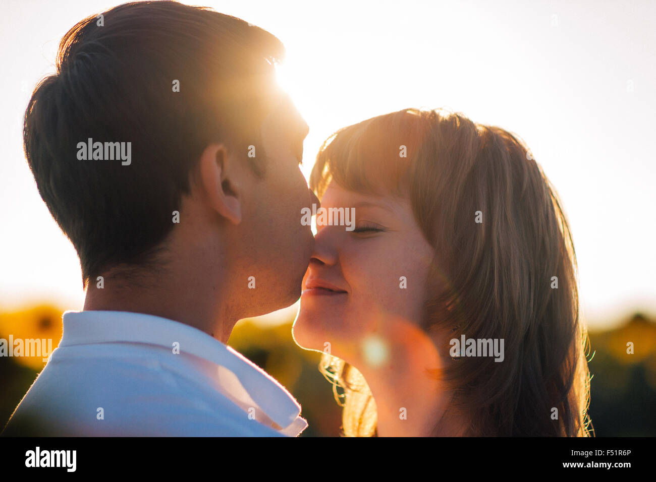 Romantic couple standing and kissing on background summer meadow ...