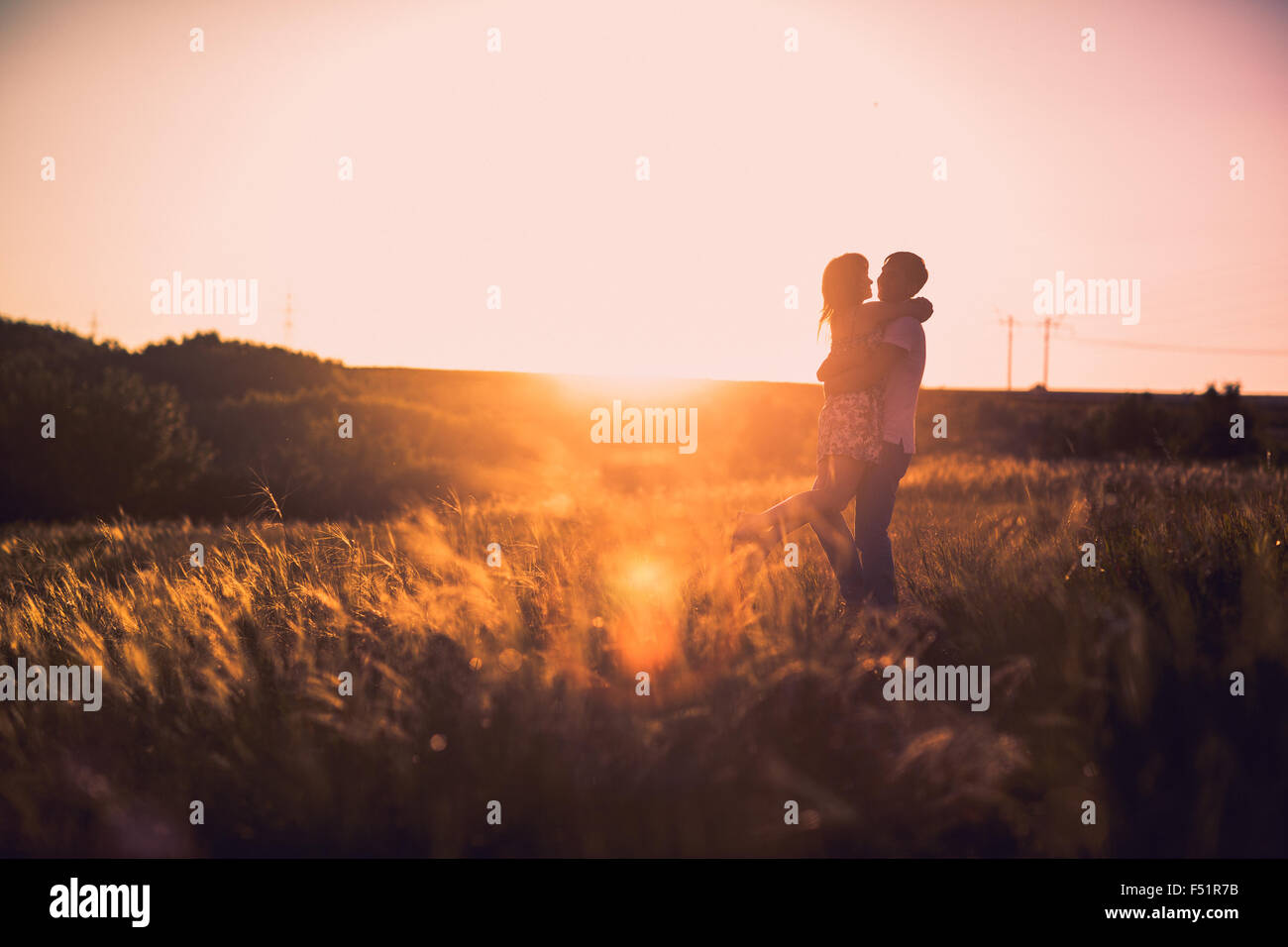 Romantic couple standing and kissing on background summer meadow sunset ...