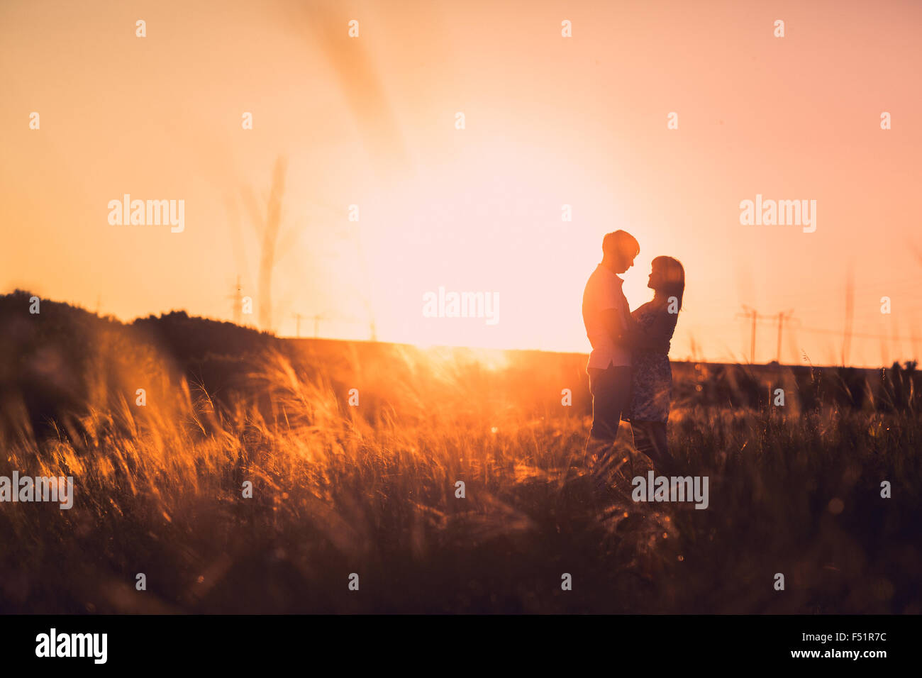Romantic couple standing and kissing on background summer meadow sunset ...