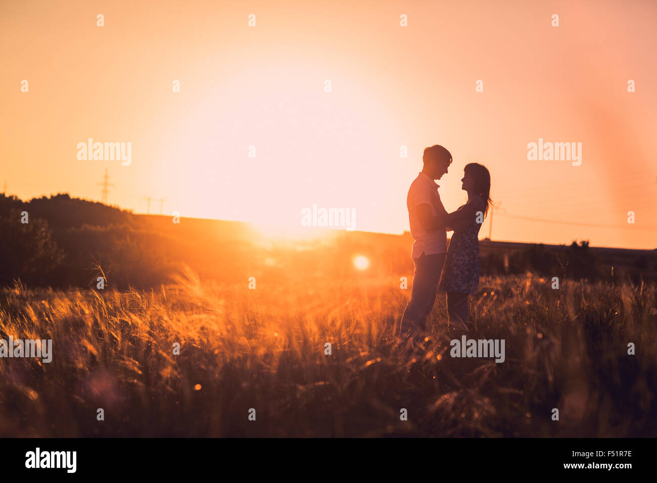 Romantic couple standing and kissing on background summer meadow sunset ...