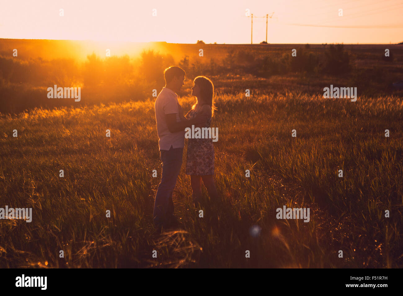 Romantic couple standing and kissing on background summer meadow sunset ...