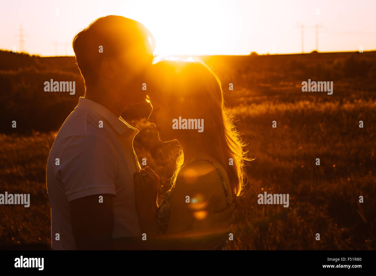 Romantic couple standing and kissing on background summer meadow sunset ...