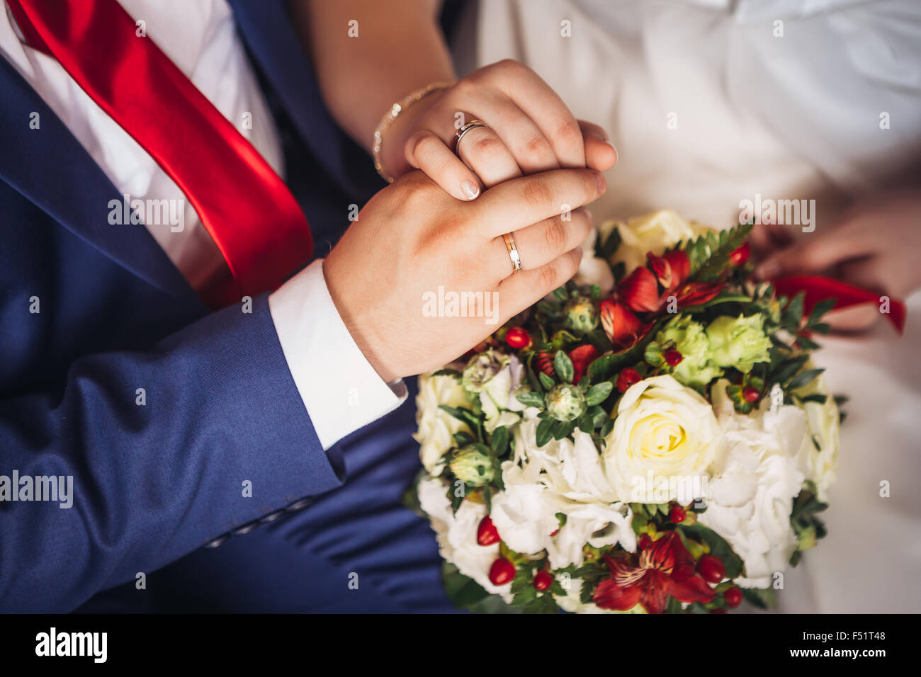 hands of bride and groom on the bouquet Stock Photo - Alamy