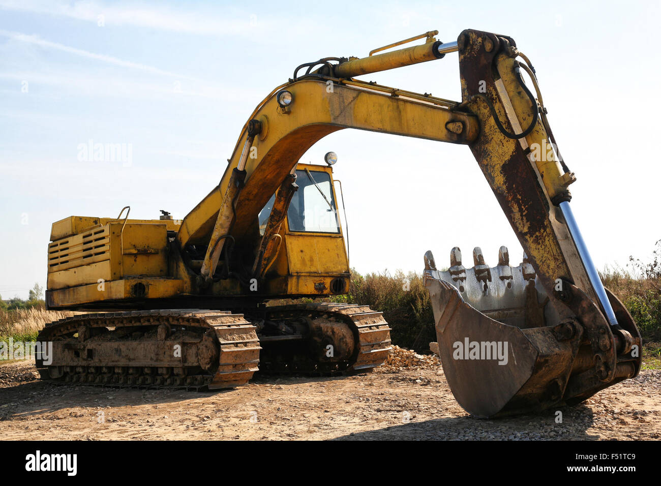 The old yellow track excavator thrown into a field. Stock Photo