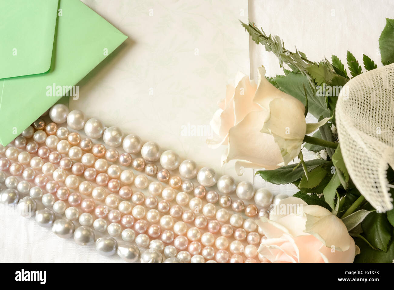 Pink roses lying on the table with an empty letter and a pink pearl necklace genuine of Japan. Stock Photo