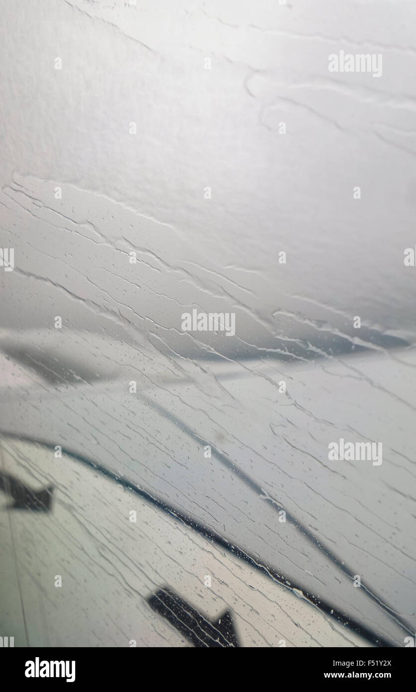 Rain drops on airplane window, wing out of focus, Netherlands. Stock Photo