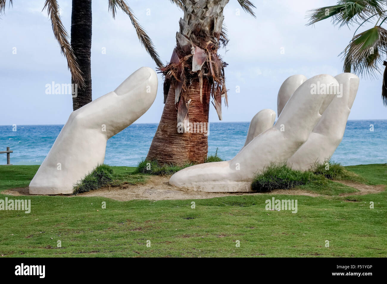 Statue caring open hand around palm tree, mediterranean beach