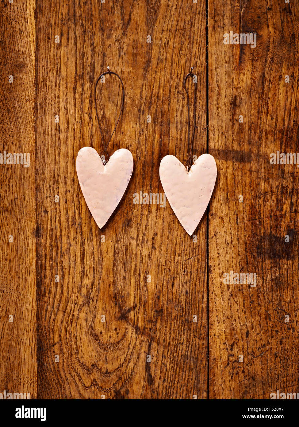zwei Herzen aus Blech auf braunem Tisch Stock Photo