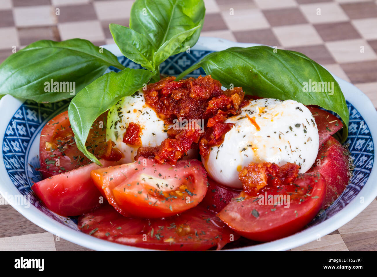 close up of a fresh mozzarella tomato salad with green basil leaves ...