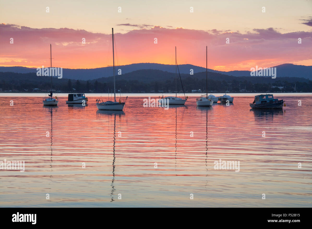 Lake Macquarie boats reflected in still water at sunset Watagan mountains in background New South Wales NSW Australia Stock Photo