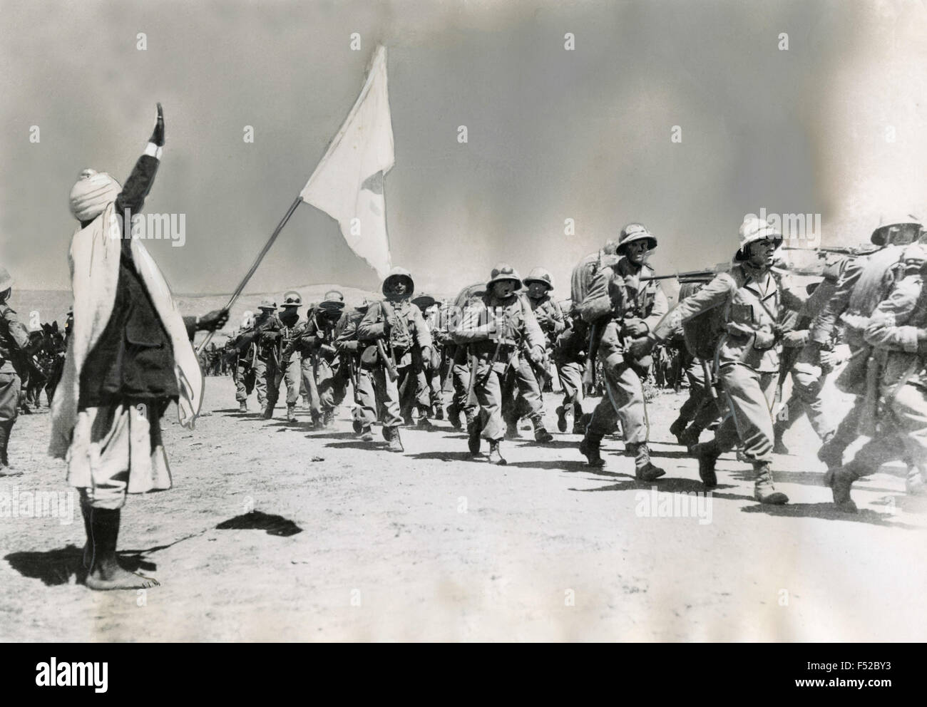 An Ethiopian salutes the Italian troops with a white flag , Makale , Ethiopia Stock Photo