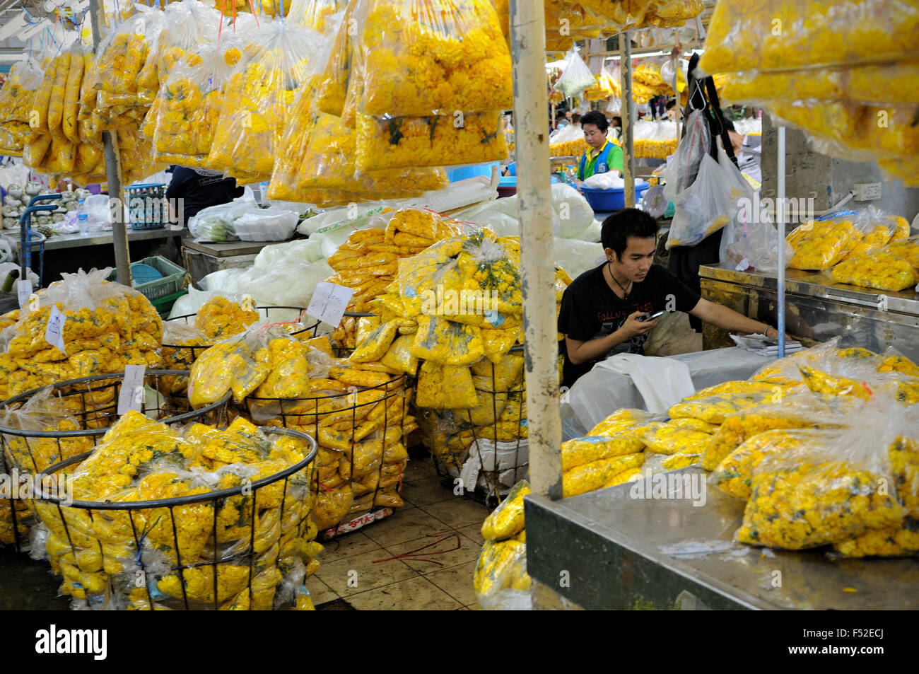 Young man and yellow flowers inside bags at Pak Khlong Talat, a flower market in Bangkok, Thailand Stock Photo