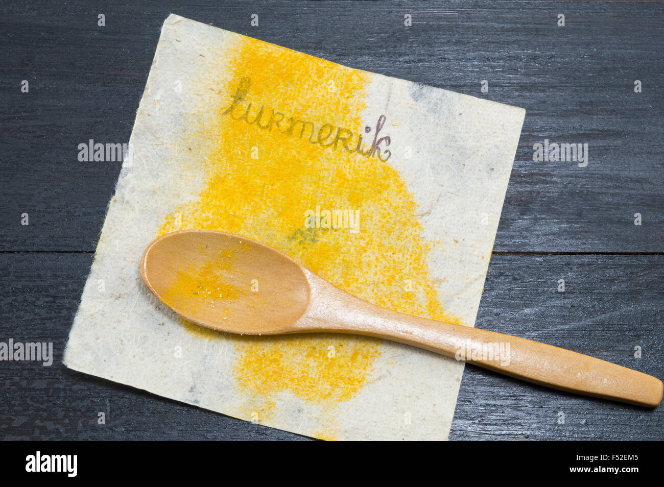 Turmeric spice on labeled recycled paper and a wooden spoon Stock Photo