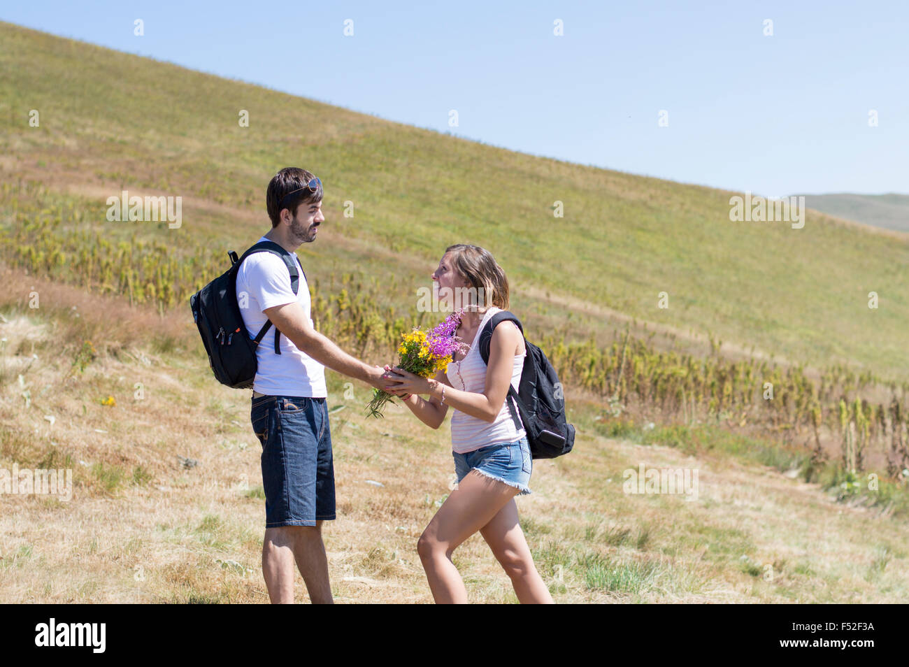 Hiker gives flowers to a woman on a hiking trip at the mountain Stock Photo