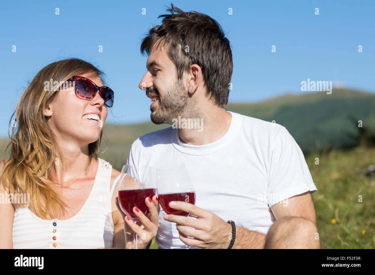 Young happy couple drinking wine on a hiking trip at the viewpoint Stock Photo