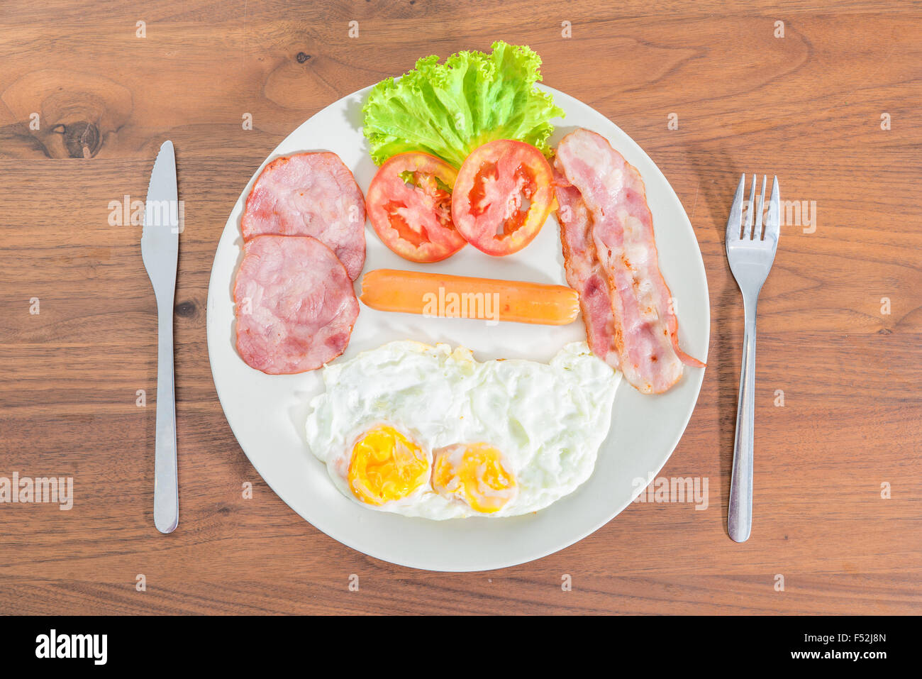 English breakfast with fried eggs, bacon, sausages, ham and fresh salad Stock Photo