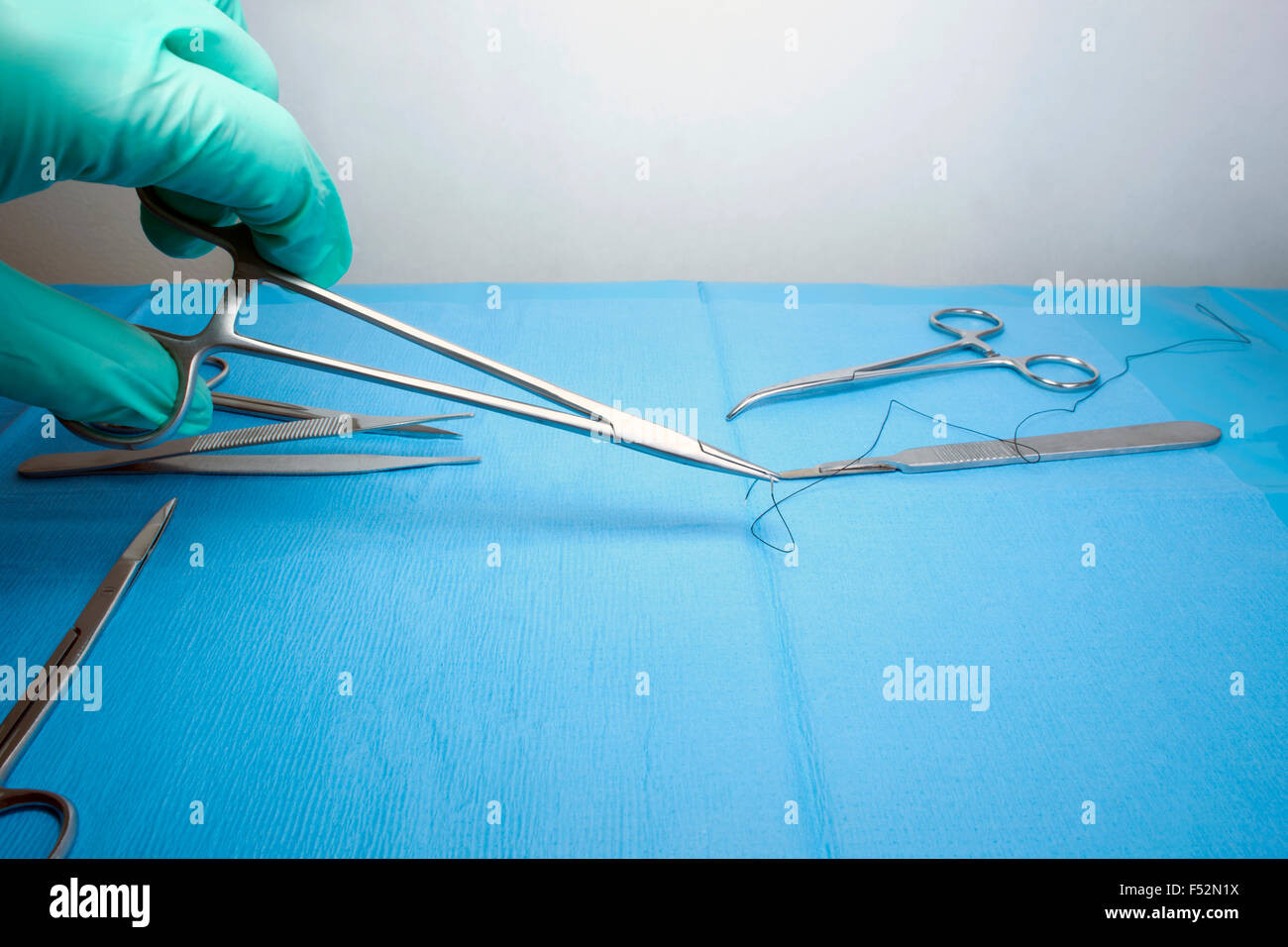 Needle holder with suture picked up from sterile field by technician
