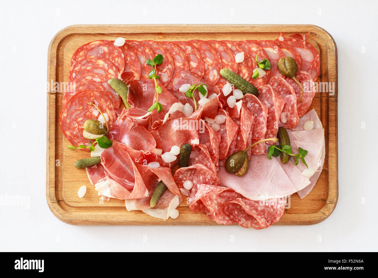 Top view of Charcuterie board - A platter of ham & bacon slices with pickles on a wooden board Stock Photo