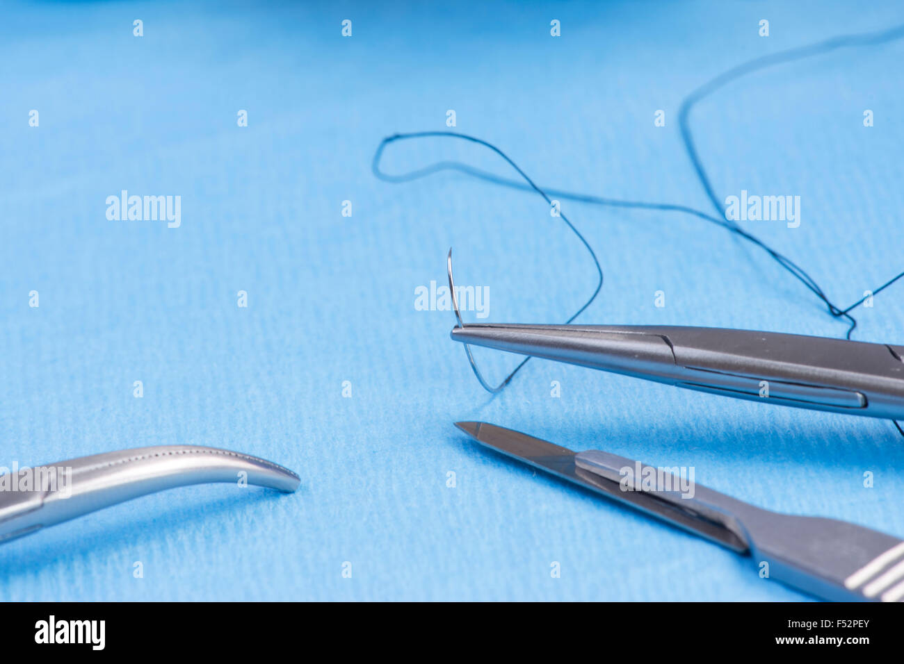 Needle holder with silk suture on blue sterile drape Stock Photo Alamy