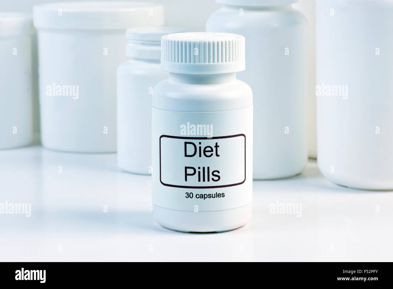 White diet pill container with pill containers in background. Stock Photo