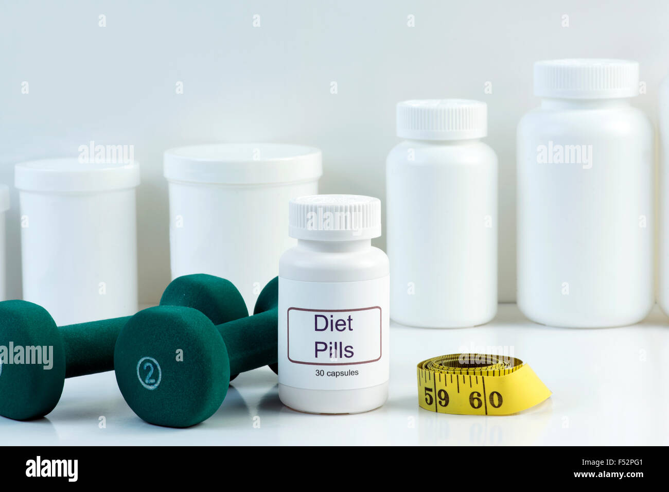 White diet pill container with weights and tape measure. Stock Photo