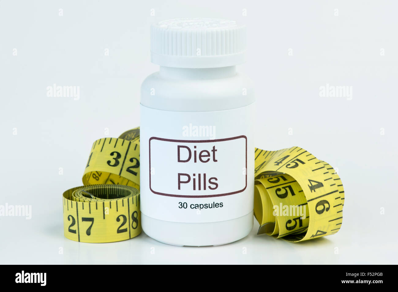 Container of diet pills with yellow tape measure. Stock Photo