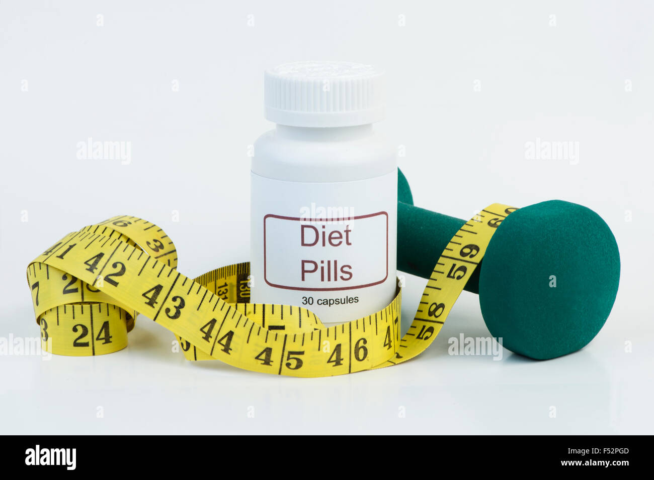 Container of diet pills with yellow tape measure and weight. Stock Photo