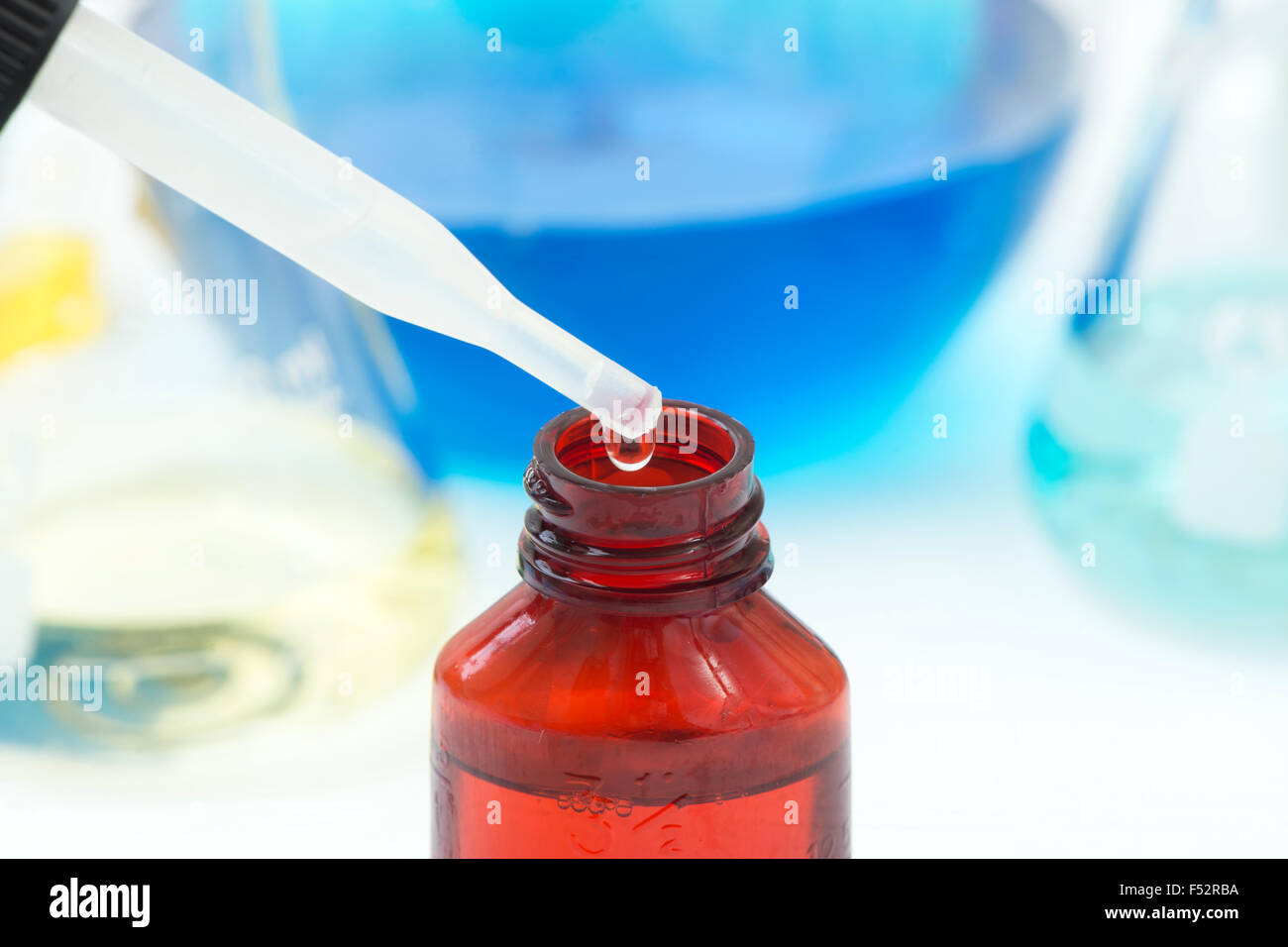 Dropper with chemical reagent being added to bottle of liquid. Stock Photo