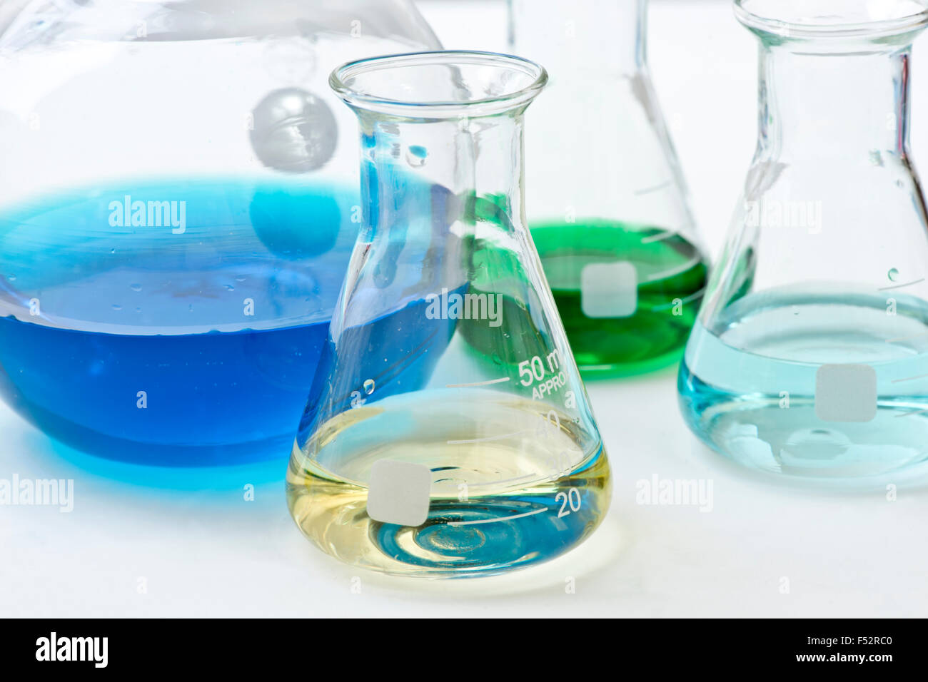Laboratory flask with light yellow liquid and more colored reagents in ...
