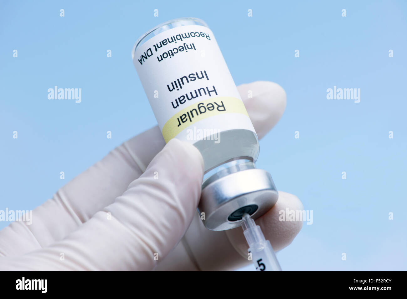 Gloved nurse's hand draws regular insulin into insulin syringe. Stock Photo