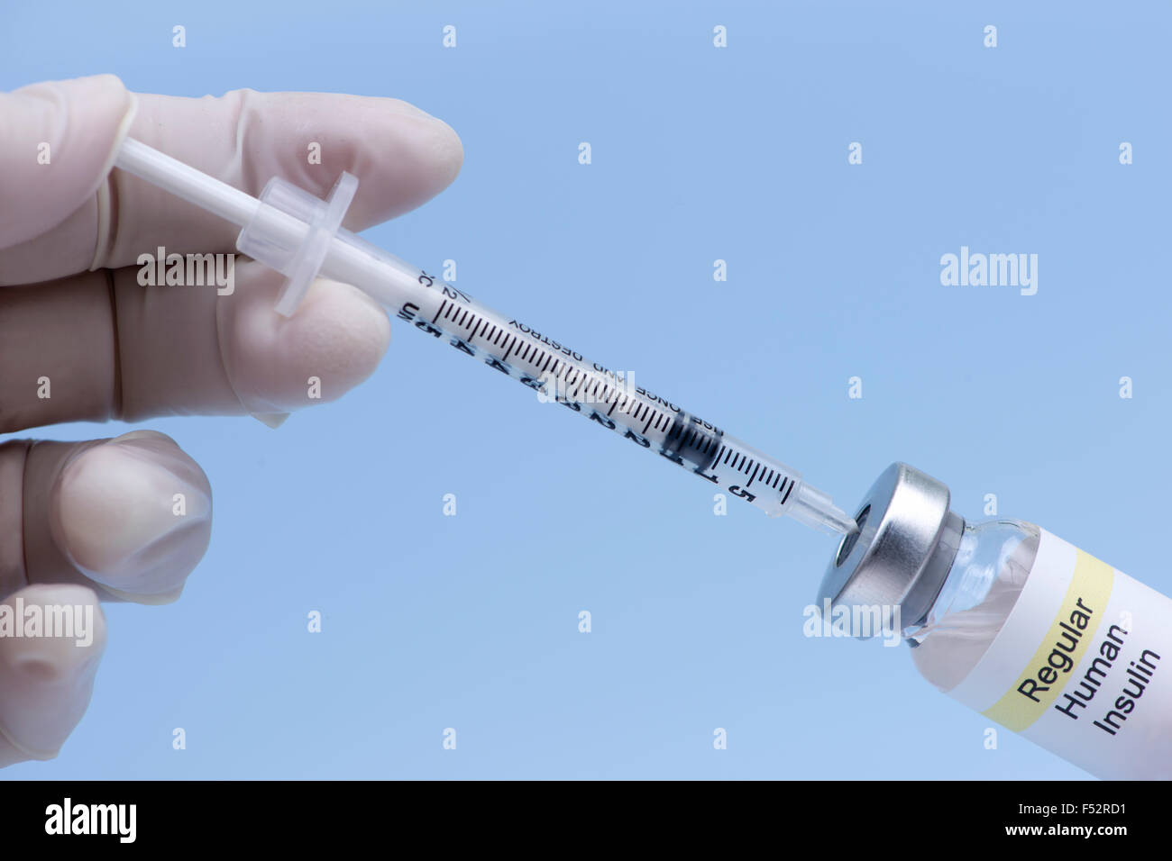 Nurse injects air into regular insulin vial prior to drawing medication. Stock Photo