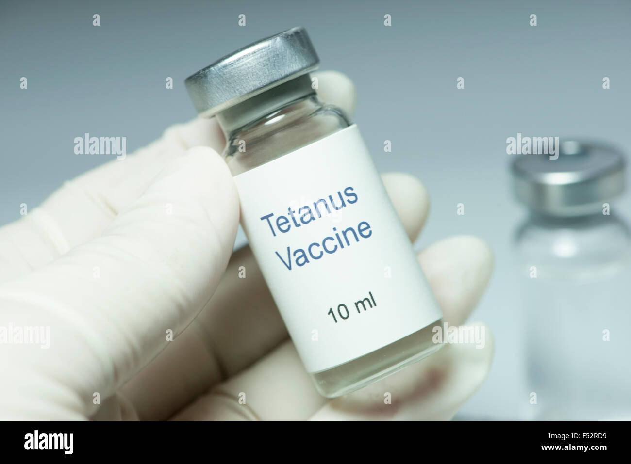 Tetanus vaccine in glass vial with gloved hand. Stock Photo