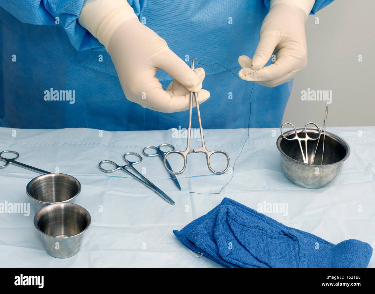 Surgical technician prepares needle holder and suture for use during