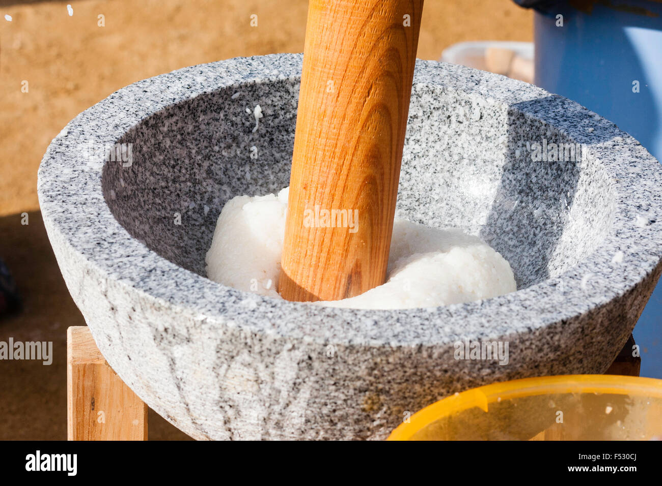 Japan. Omochi, rice bashing festival. Close-up, usu, mortar with rice being hit by wooden Kine, mallet. Outdoors sunlight. Stock Photo