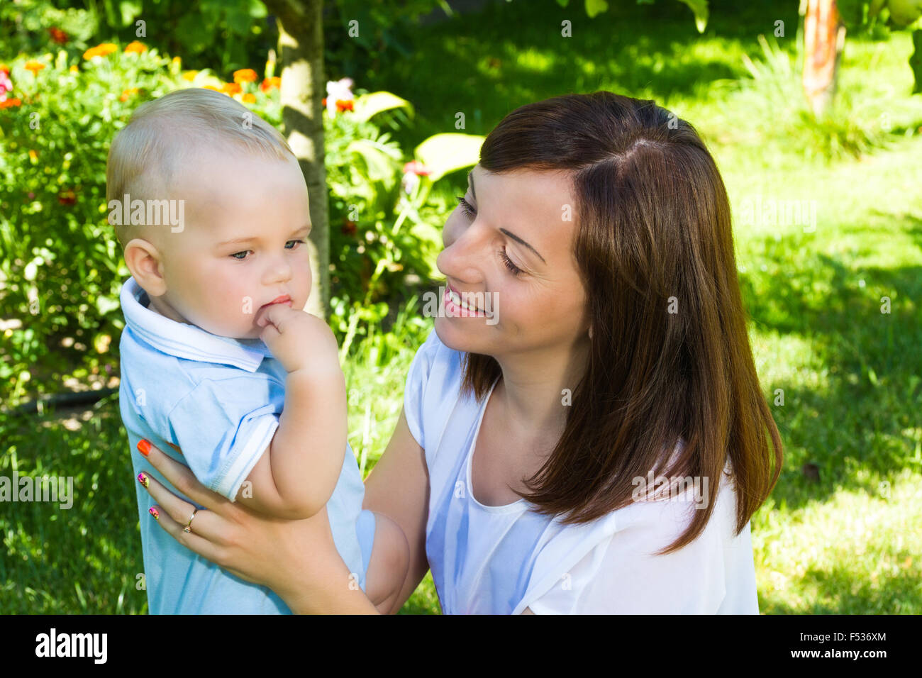 charming caucasian baby boy with mother in garden Stock Photo