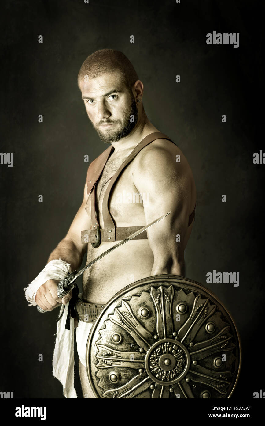Gladiator posing with shield and sword in a dark background Stock Photo ...